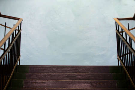 Wooden old staircase and light concrete wall.