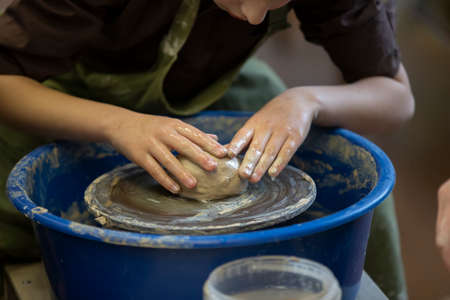 Potter's hands at work. Close-up of a potter's hands with a product on a potter's wheel. Working with clay.の写真素材