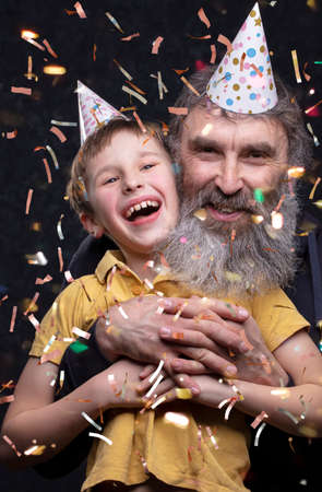 Portrait of a happy grandfather with a beard and grandson of the birthday boy on a black background.