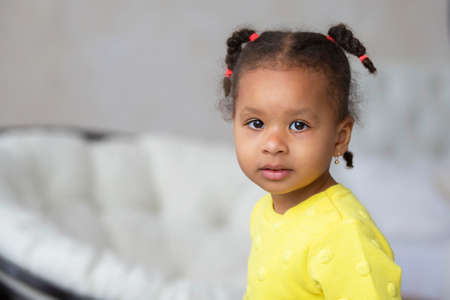 Little African American girl in a yellow dress looks at the camera.の写真素材