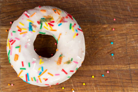 Creative sweet food. Glazed colorful donut on a wooden background.