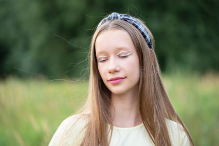 Portrait of a teenage girl with creative makeup and long blond hair on a nature background.の写真素材