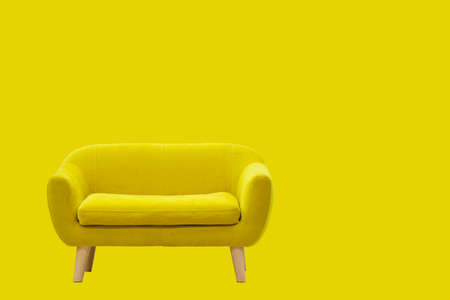 Yellow sofa on wooden legs on a yellow background.の写真素材