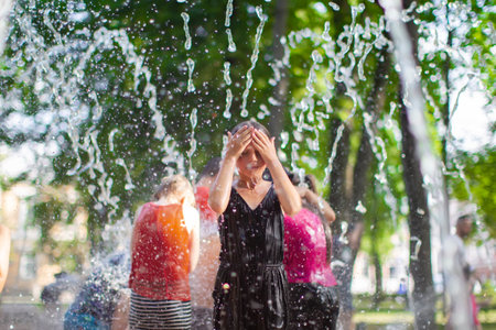 Belarus, city of Gomil, July 17, 2021. Central Park. The girl enjoys the cold waters of the fountain...