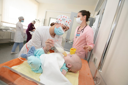 A newborn baby is being fed by a nurse in a hospital. Children's department of the hospital for newborns.のeditorial素材