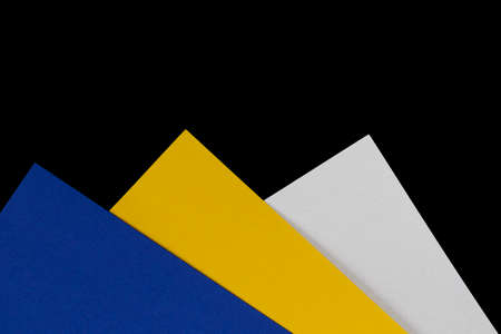 Multi-colored paper. Blue, yellow and white cardboard boxes on a black background.の写真素材