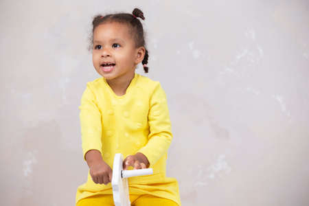 Little African American girl in yellow clothes shows tongue. Funny child.の写真素材