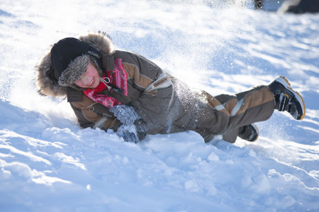Happy little boy is rolling down a snow slide. child in winter.の写真素材