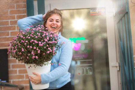 A beautiful girl is holding a large bouquet of flowers and smiling. Happy young woman in the city.の写真素材