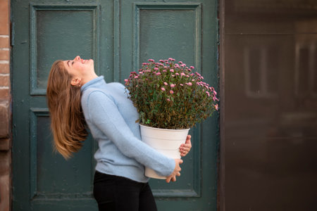 A beautiful girl is holding a large bouquet of flowers and smiling. Happy young woman in the city.の写真素材