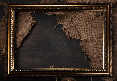In a beautiful frame, a coarse weave fabric on a wooden background. background for the inscription.の写真素材
