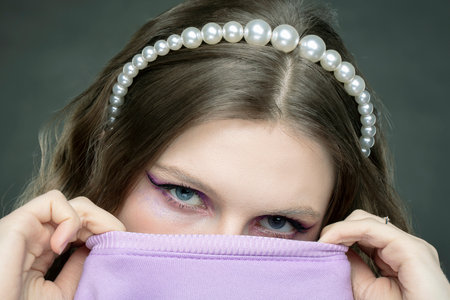 Eyes of a beautiful female model. Cover half of your face with a sweater.の写真素材