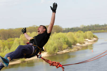 A man makes an extreme jump from a bridge on a rope.の写真素材