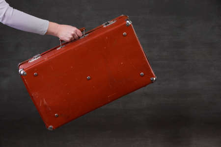 In hand is a brown retro suitcase on a gray background.の写真素材