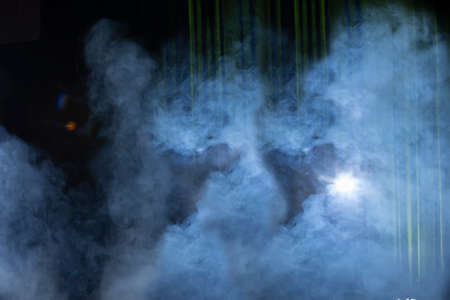 Green theatrical background with beam of light and blue smoke.
