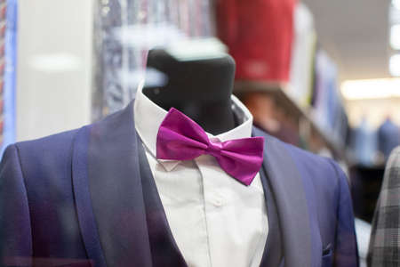 In the shop window is a mannequin in a formal suit and bow tie.の写真素材