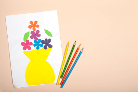 paper crafts for kids. Application of children's creativity. Kindergarten and craft school. On a beige background, a vase and flowers made of colored paper.の写真素材