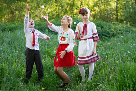 Ukrainian or Belarusian children in embroidered shirts play in the meadow.のeditorial素材