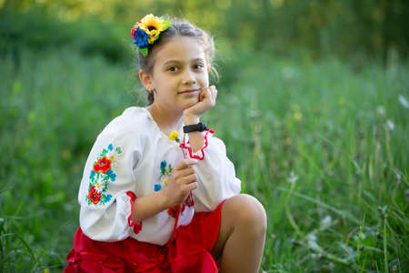 A little Ukrainian and Belarusian girl in an embroidered shirt on a summer background.の写真素材