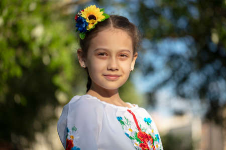 A little Ukrainian and Belarusian girl in an embroidered shirt on a summer background.の写真素材