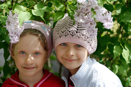 Belarus, Gomil city, May 16, 2016. City street. Two little girls-girlfriends by the lilac bush and smiling.のeditorial素材