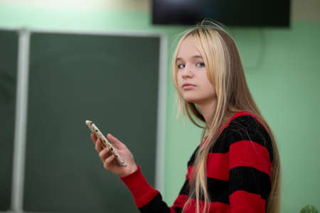 Teenager of senior school age. A teenage girl stands in front of a blackboard.