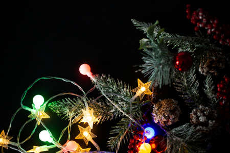 Christmas background with lights and a Christmas tree branch. Christmas multicolored lights on a black background.の写真素材
