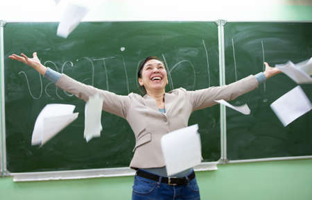 Happy teacher scatters papers before the holidays.
