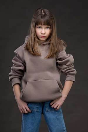 Beautiful teen girl in jeans on a gray background.