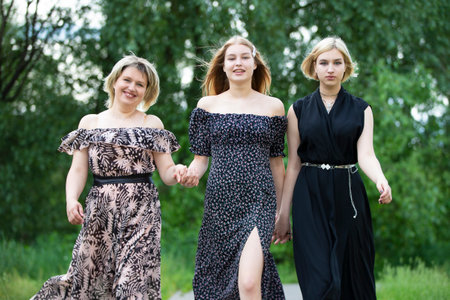 A happy mother with two adult daughters walk along the road and smile.のeditorial素材