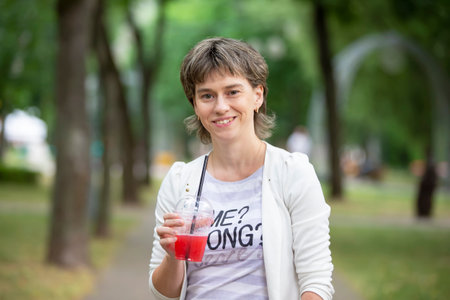 June 23, 2019 city of Gomil. city street. A middle-aged woman with a cup of coffee walks down the street and smiles.のeditorial素材