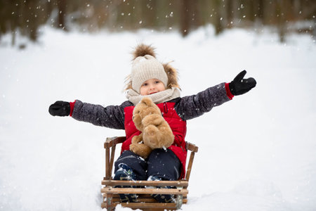 A little boy sits in a wooden sled against the backdrop of winter nature.