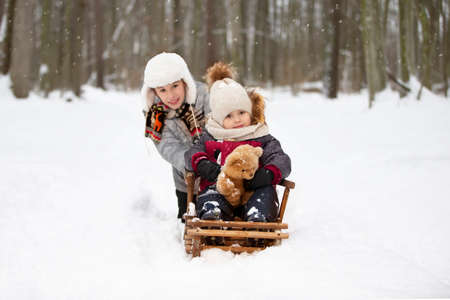 Children on a wooden sled on a winter day. Active winter kids outdoor gamesの写真素材