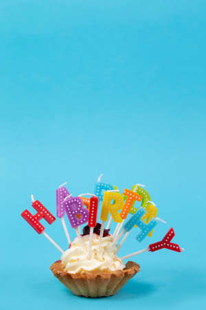 Cupcake with rainbow-colored candles for a birthday with the inscription Happy birthday