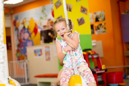 A little girl rides a rope in a children's center.の写真素材