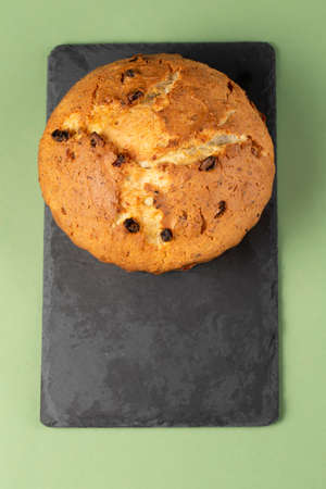 Classic cottage cheese pie with raisins. On top of a cupcake on a black cutting board.