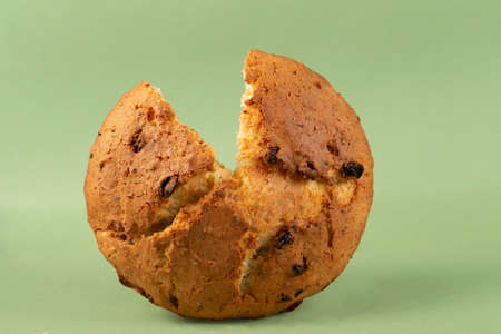 Classic cottage cheese pie with raisins.Cupcake with a cut piece on a green background.
