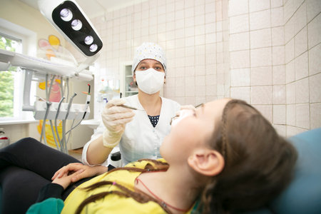 The doctor treats the patient's child's teeth.Child in the dentist officeの写真素材