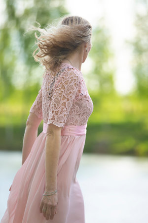 A beautiful woman in a flowing pink dress stands on her back to the camera.の写真素材