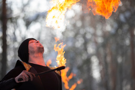 The man has fire and smoke coming out of his mouth. Fireshow. Young man blowing fire from his mouth