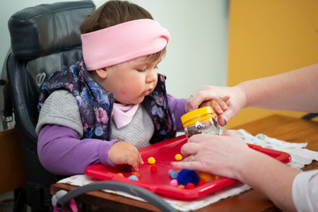 May 31, 2021 Belarus, Gomil, Children's Rehabilitation Center. A psychologist works with a small child with mental retardation.のeditorial素材