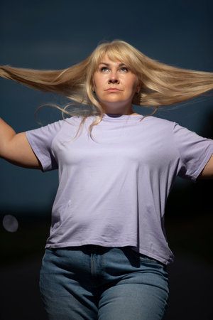 Plump middle aged woman posing in jeans on the street, overweight xxl. A full girl enjoys life.の写真素材