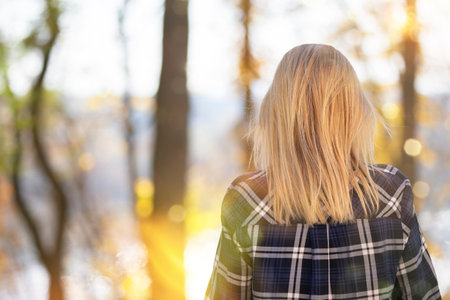 A woman stands with her back against the background of autumn. A girl walking in the forest in...