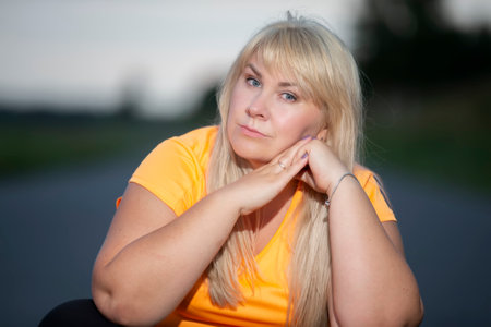 Portrait of a European middle-aged woman in a tracksuit, posing for the camera, relaxing. excited overweight woman in trendy tracksuit resting after exercising.の写真素材