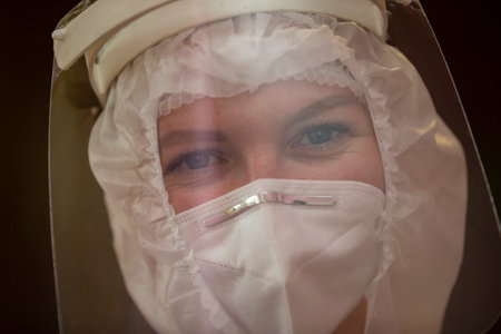 The face of a female doctor close-up in a protective suit.