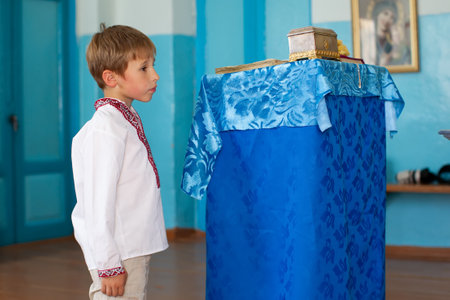 A little Belarusian or Ukrainian boy in an embroidered shirt in a church.の写真素材
