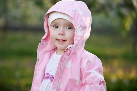 Child in the spring garden. Funny little girl on a walk.の写真素材