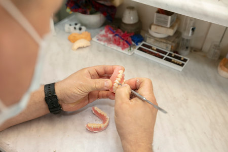 Manufacturing of dentures. Orthopedist's hands make jaw prostheses.の写真素材