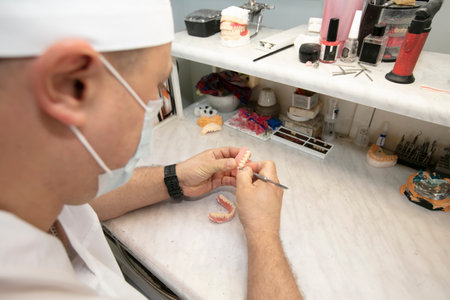 Manufacturing of dentures. Orthopedist's hands make jaw prostheses.の写真素材