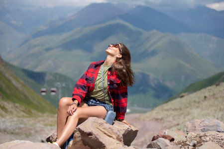 Happy female hiker on the top of the mountain enjoys the beautiful view of the mountains.の写真素材